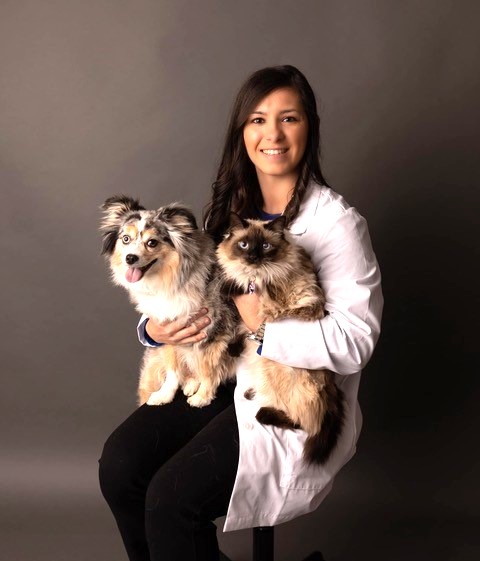 Dr. Reece sitting in a chair holding a cat and a dog in her lap 