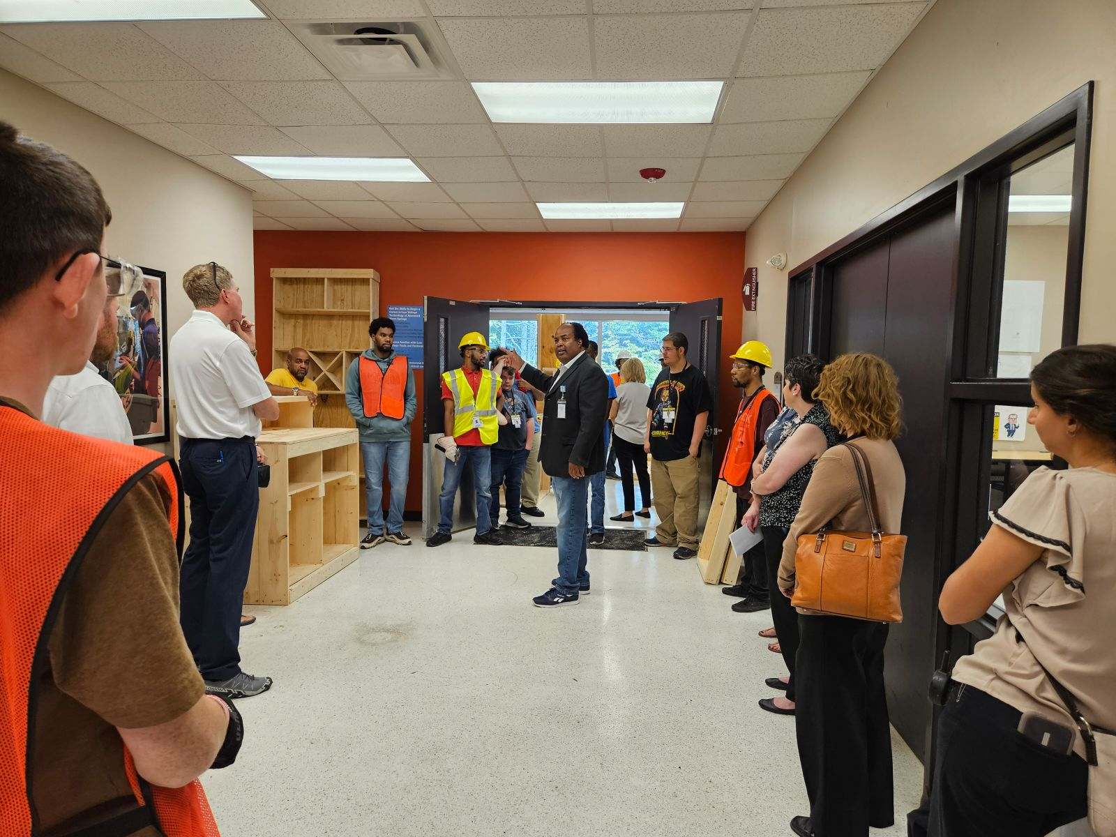 diverse group of men and women standing in a room listening to a speaker