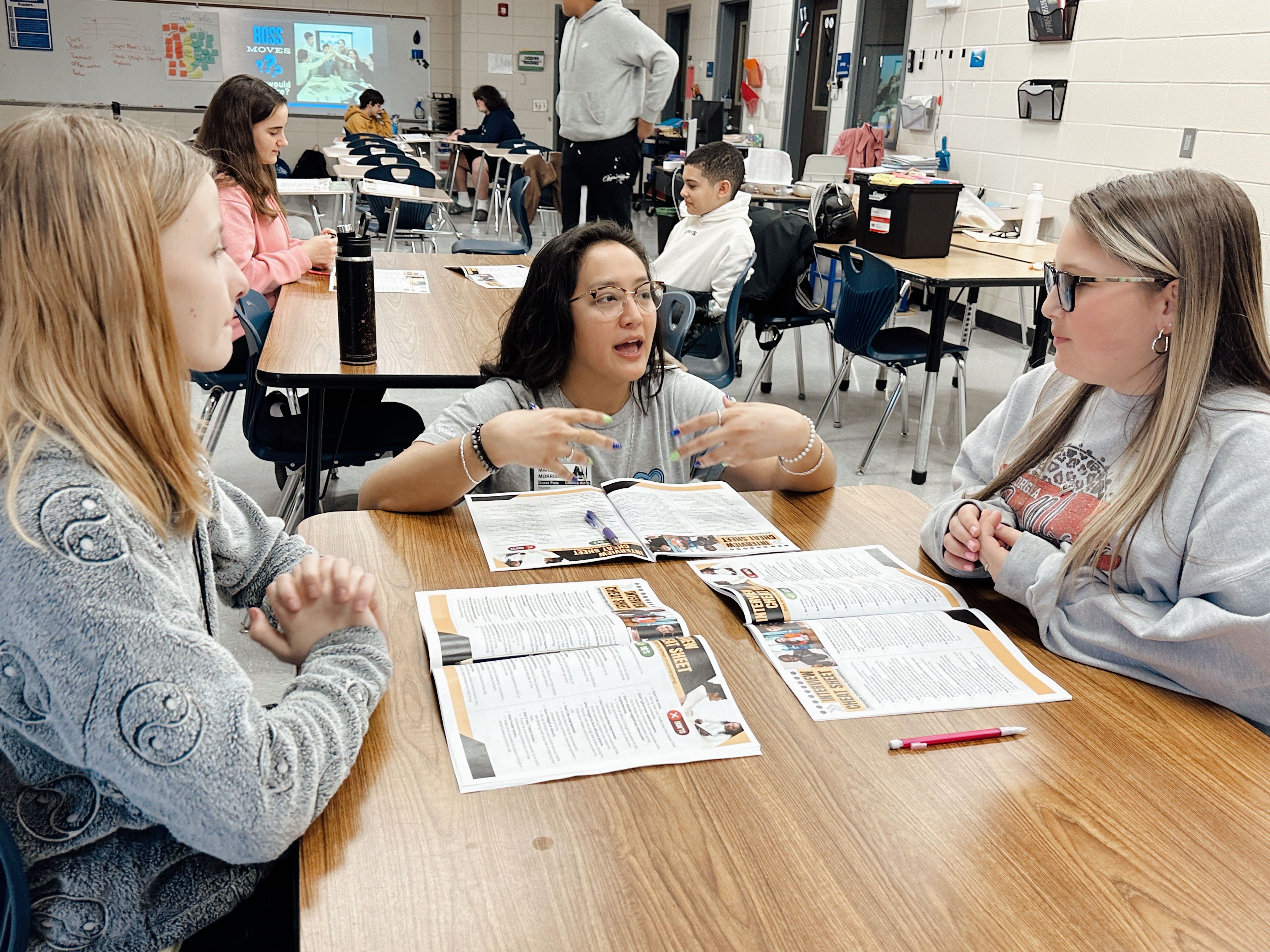 Facilitator and two students interacting at a table