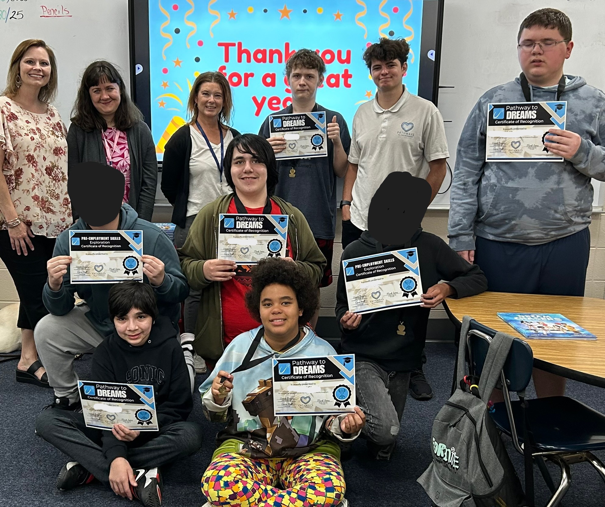 Group of students posing with certificates in front of a whiteboard. 
