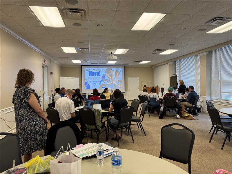 Groups of people sitting at tables looking at a presentation on a projector screen