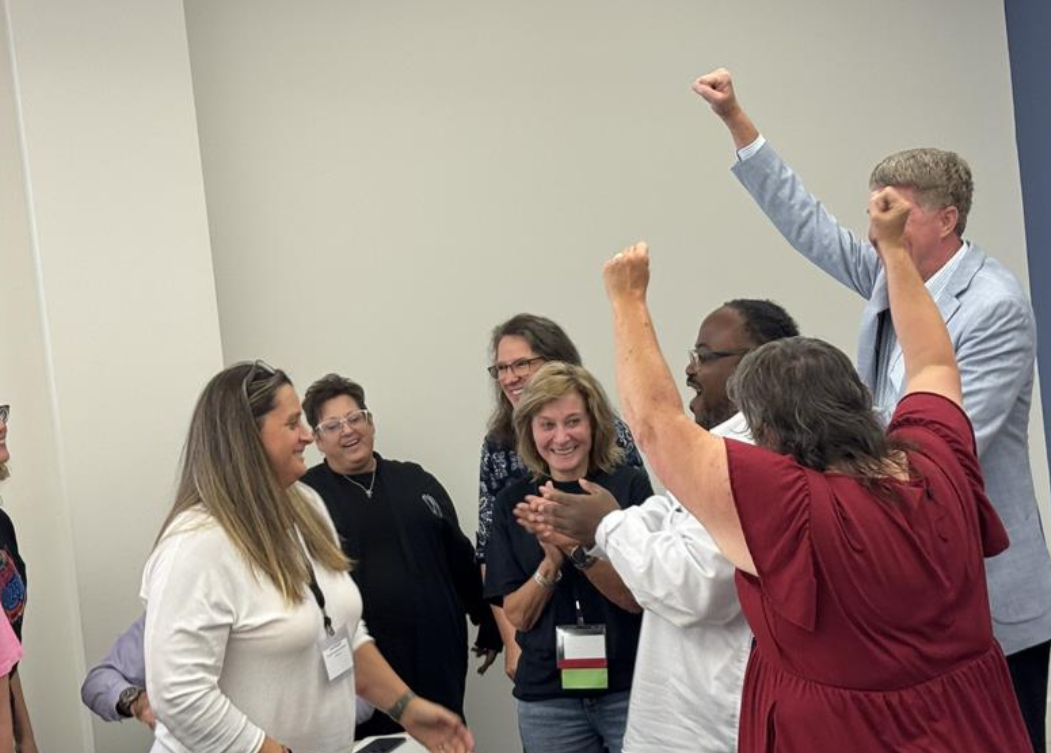 Group of adults in a room cheering from excitement.