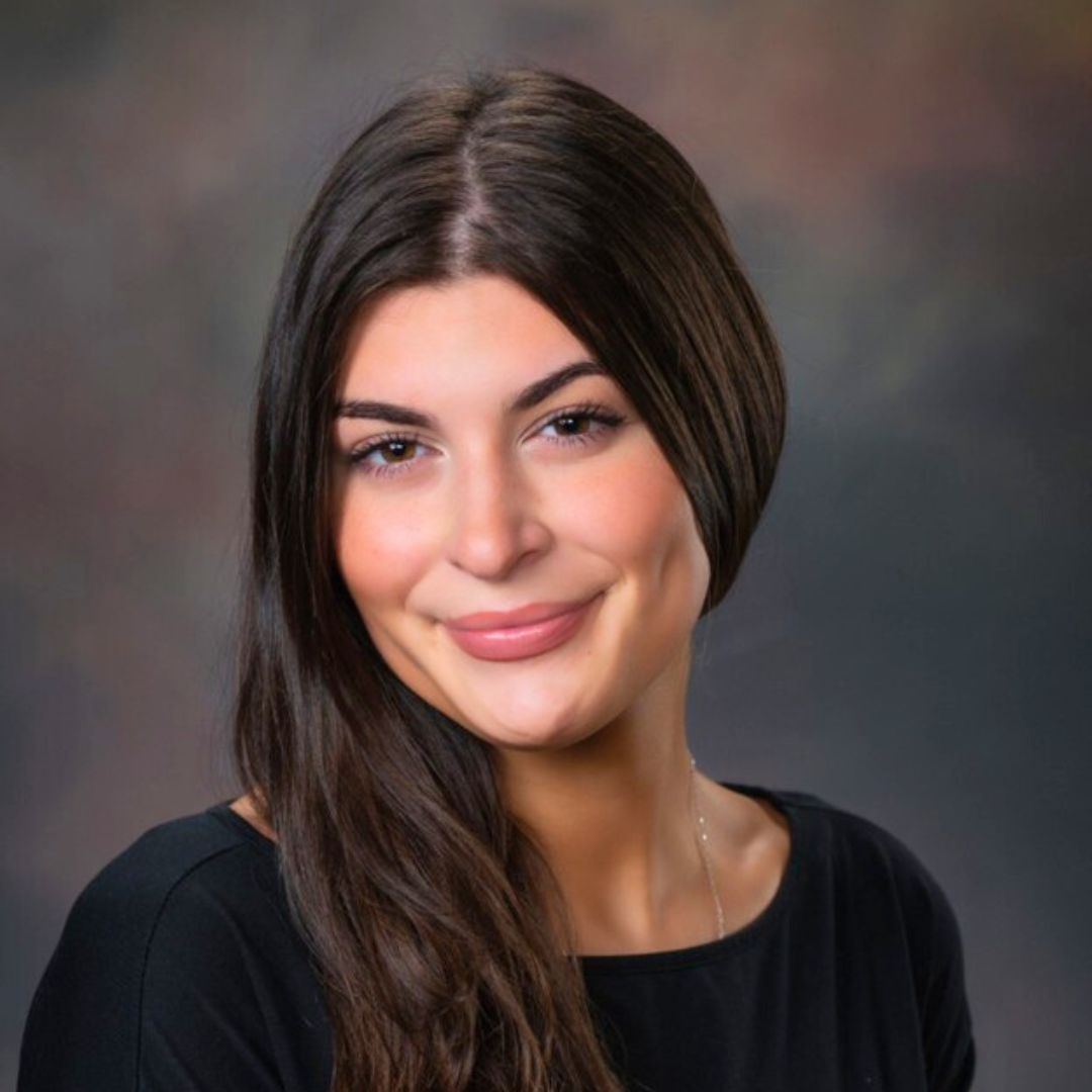 A headshot photo of a woman wearing a black shirt. 