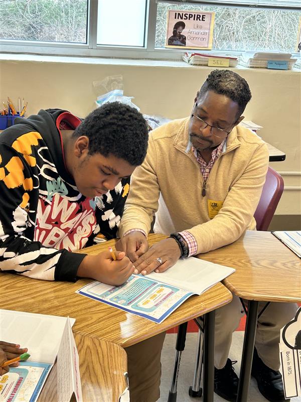 Student sits with instructor as they work on an activity in a booklet.