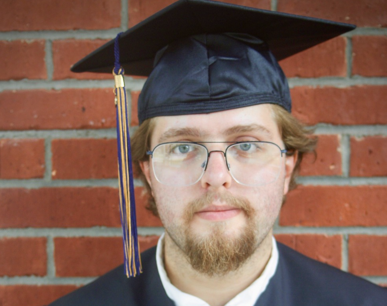A man wearing a black graduation cap and gown. 