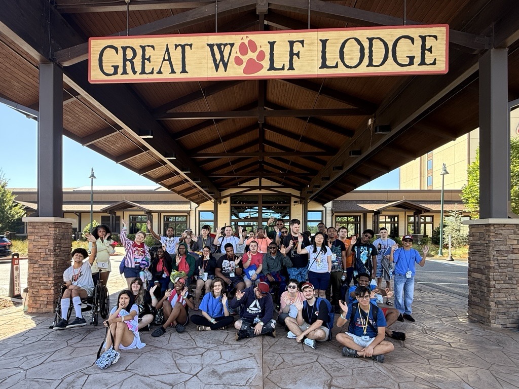 A large group of students gathered in front of the Great Wolf Lodge sign