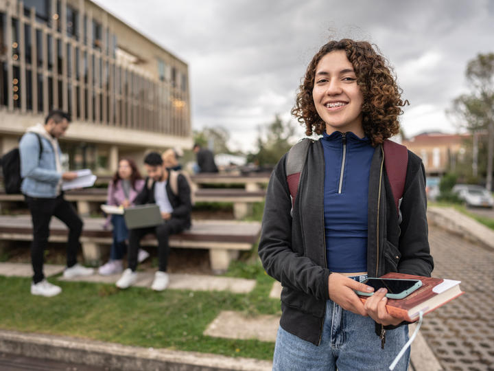 A student who is smiling while holding her book and photo in her hand. 