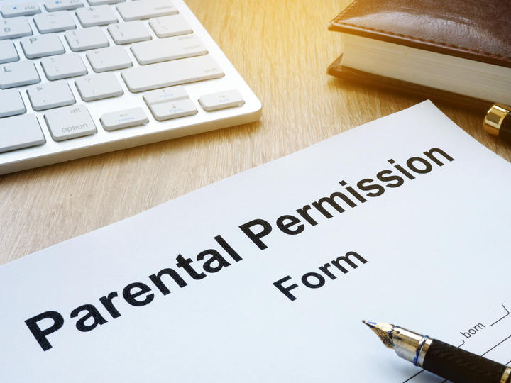 Photo of a laptop that is open and parental permission form. 