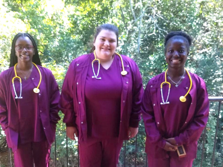 Three RWS students that have on their burgundy nurse scrubs. 