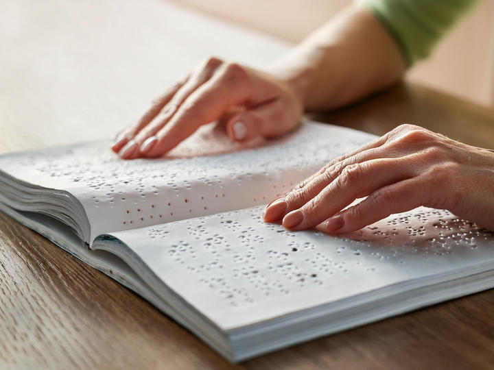 A person who hands are on a braille sign. 