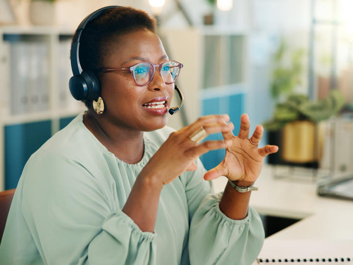 Call center employee who has black headsets on and is talking. 