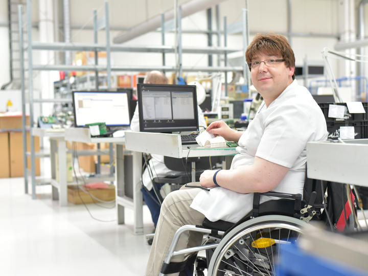 A photo of a man that is in a wheelchair smiling.