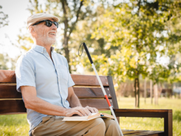 A blind man sitting on a bench and smiling. 
