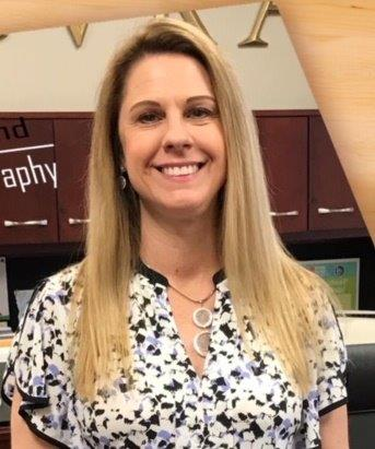 Lauri Tuten wears a floral top and smiles at the camera