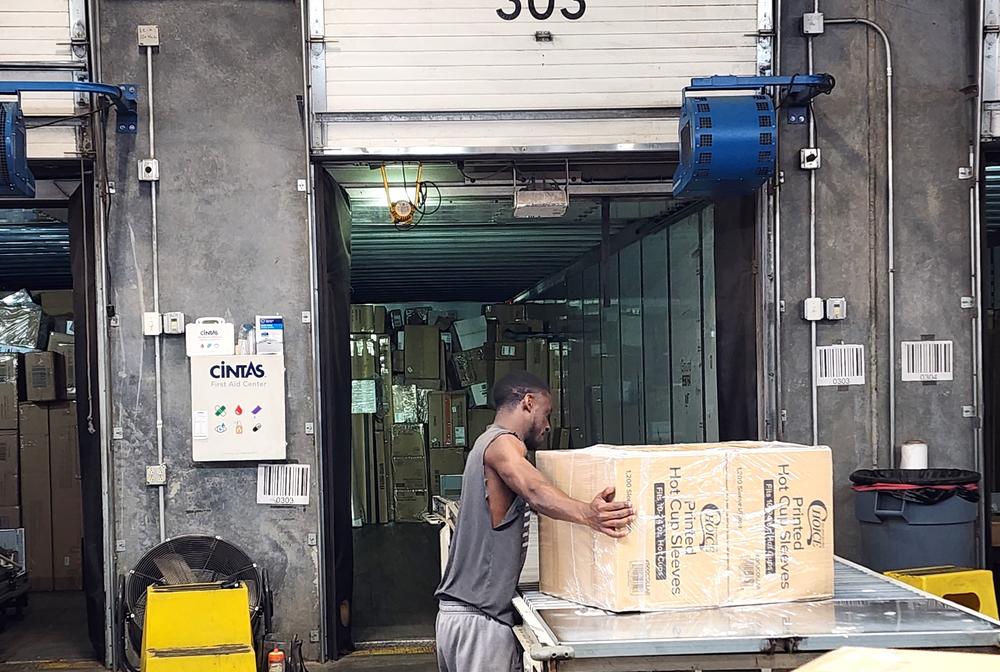 Nathan moving a box on a conveyer belt into the back of a FedEx delivery truck