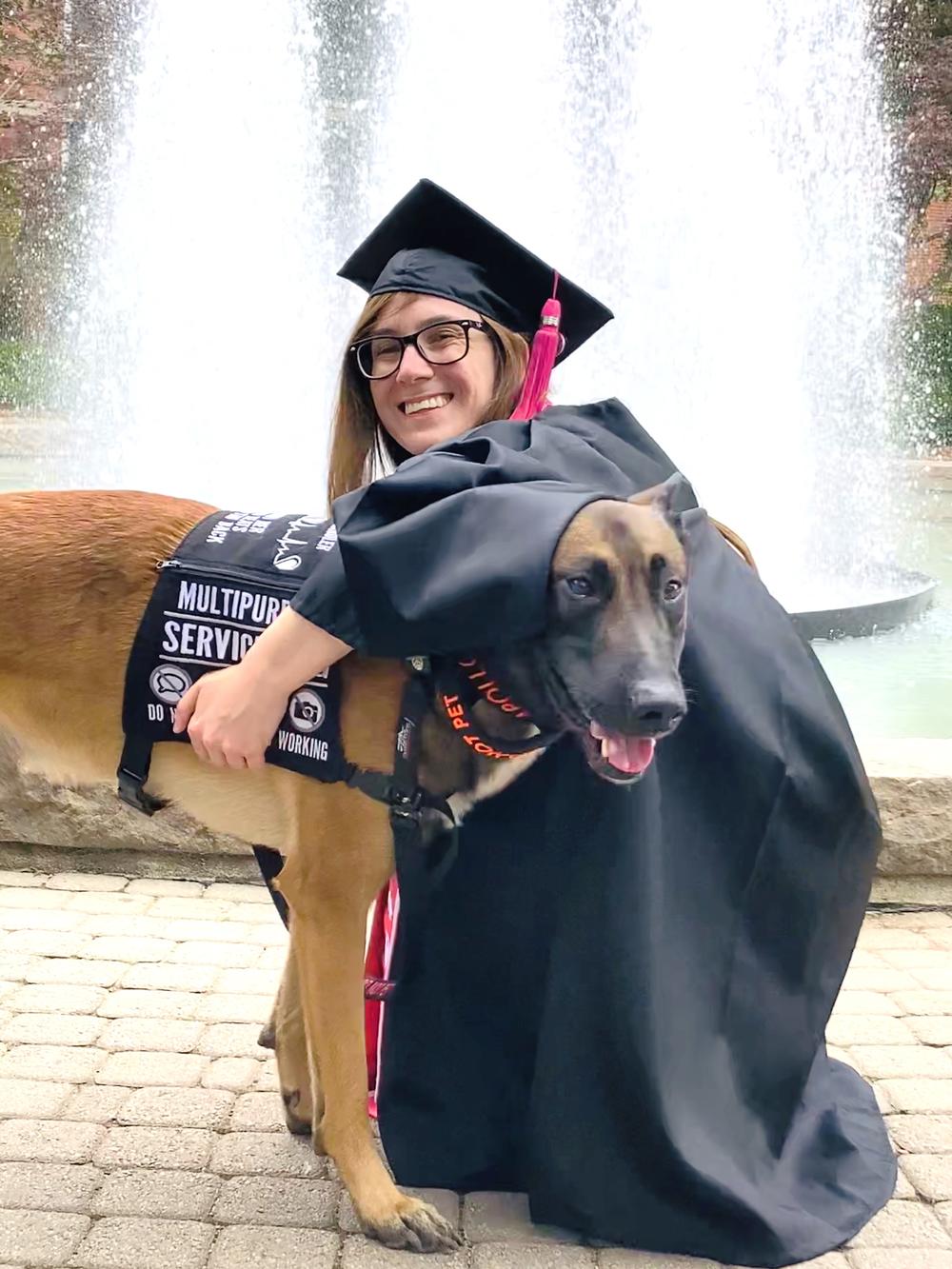 Bailey hugging service dog in front of fountain 