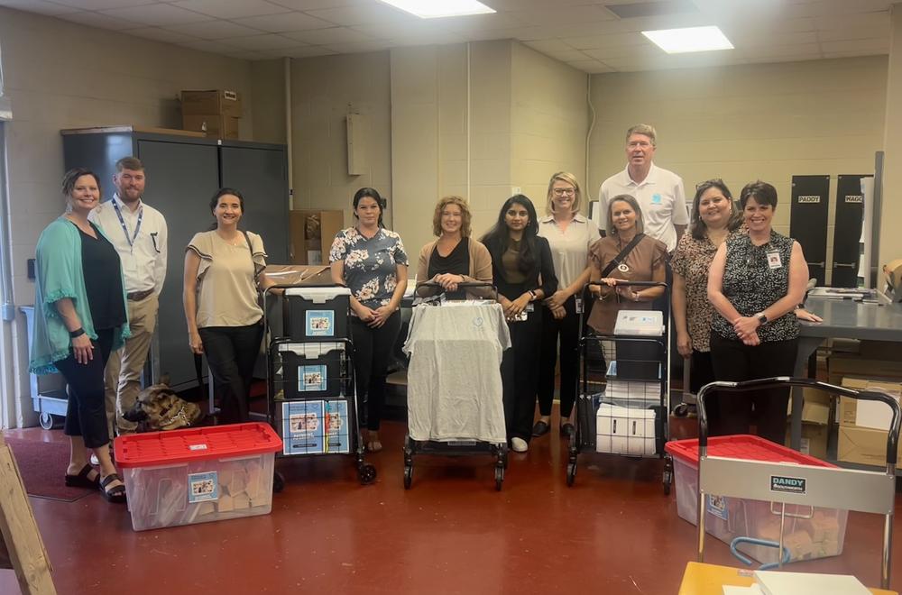 group of people standing with bins and carrying cases with P2P materials in them