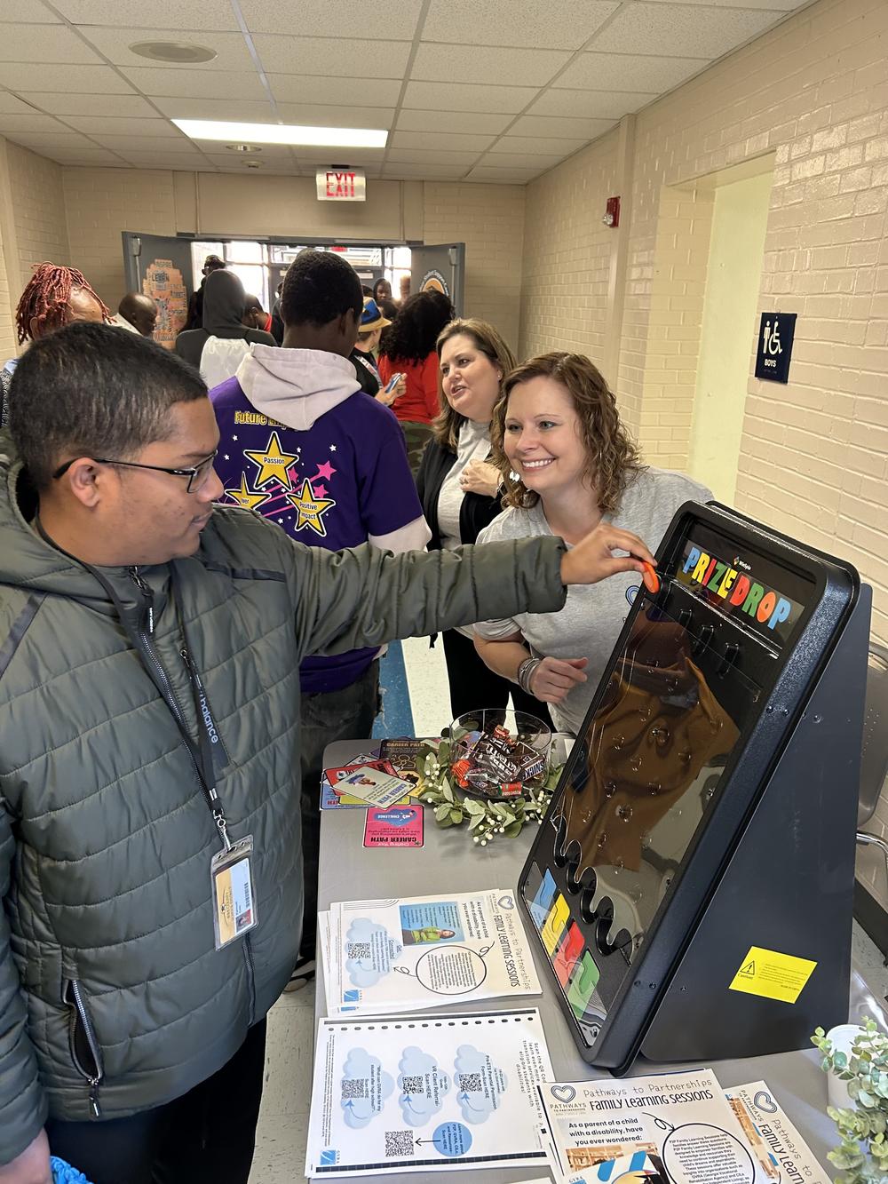 Male student playing a game with a woman looking on to assist