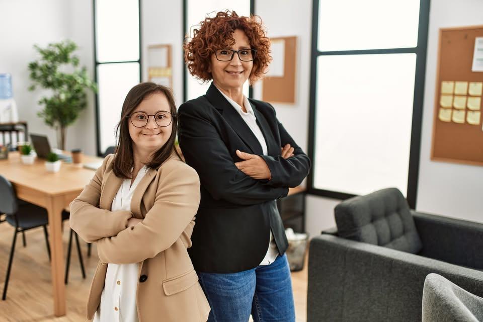 woman with dark hair standing back to back with another woman with strawberry reddish brown hair