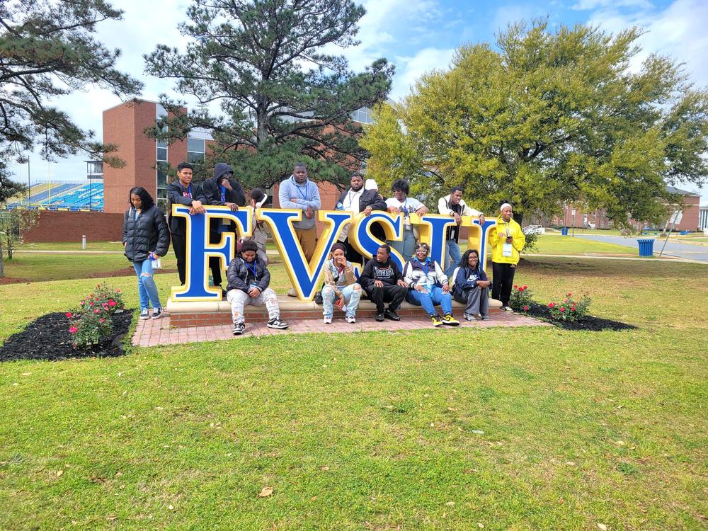 A photo of tree of life students posing in front of the FVSU sign outside. 