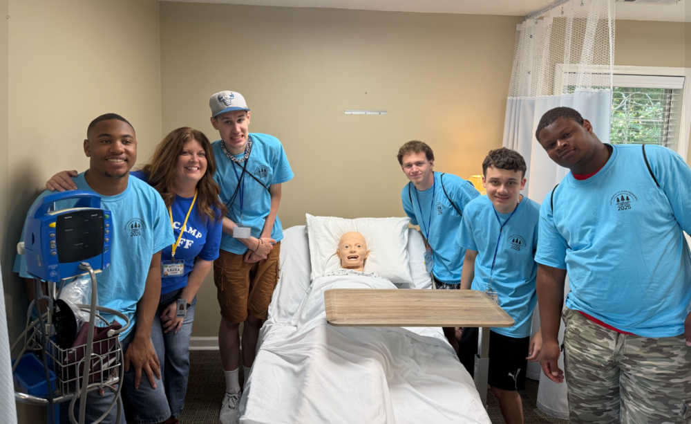 A group photo of P2P campers and staff in a hospital room.