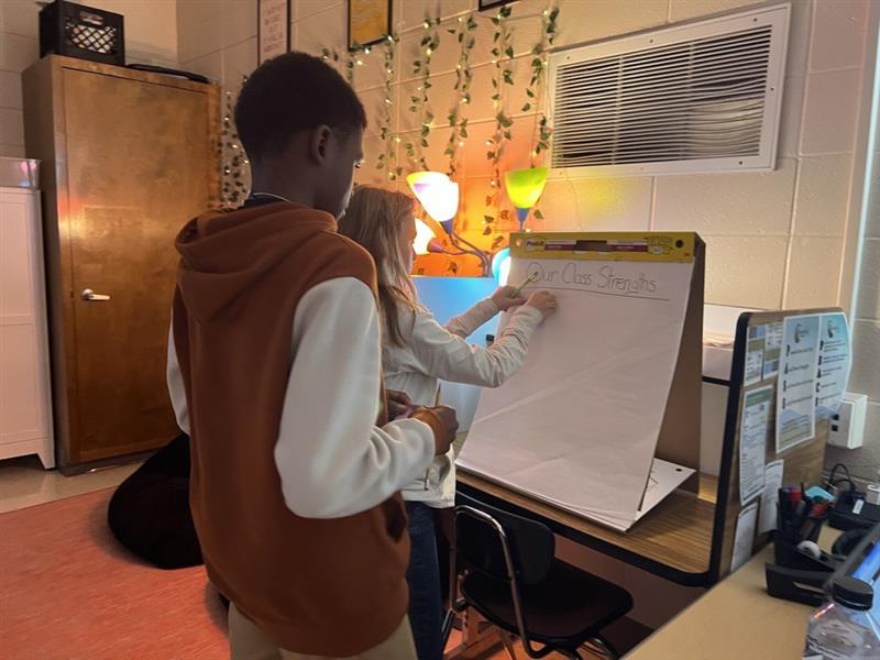2 students working together completing a task on an easel pad
