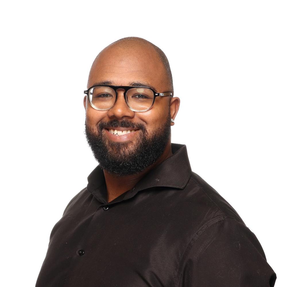 A headshot of a man in a black shirt that is smiling. 