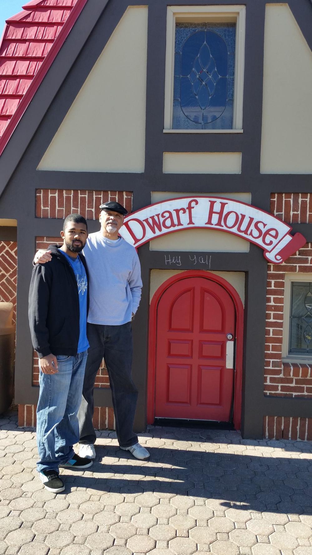 Two people standing in front of the Dwarf house building. 
