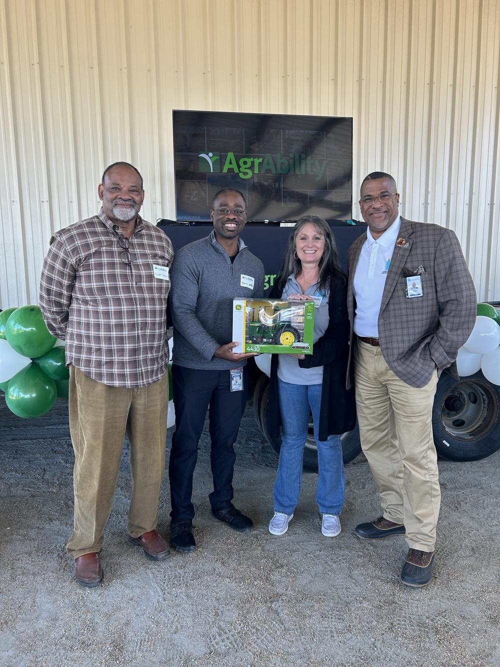 Four people standing behind a green tractor.