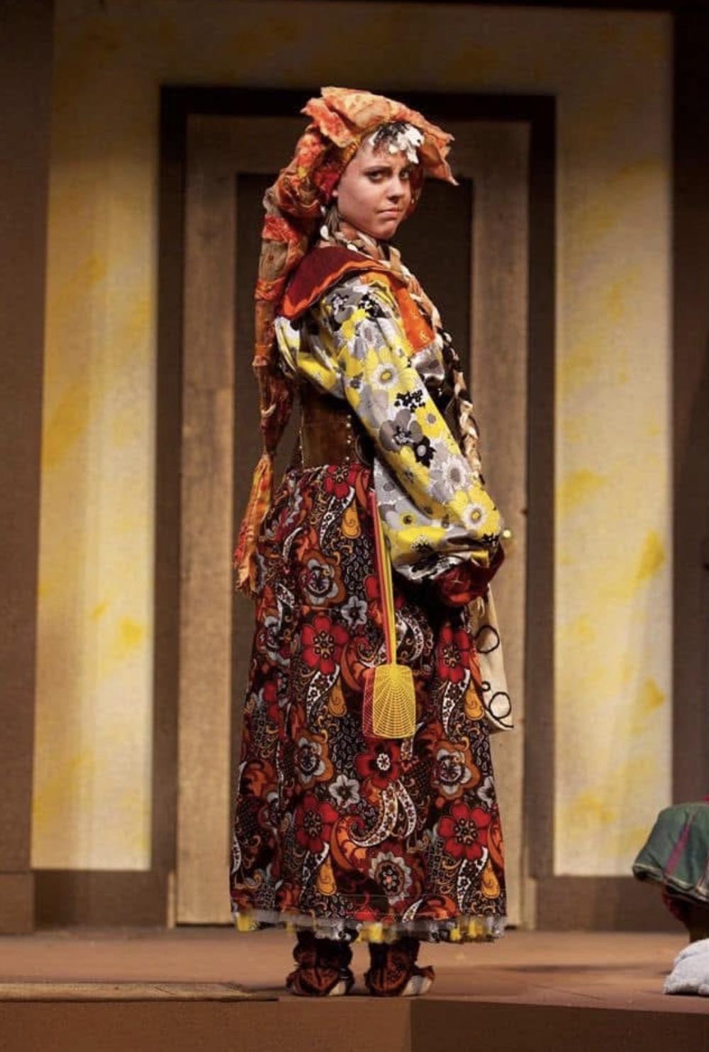 A woman dressed up in an orange, red and yellow costume. 