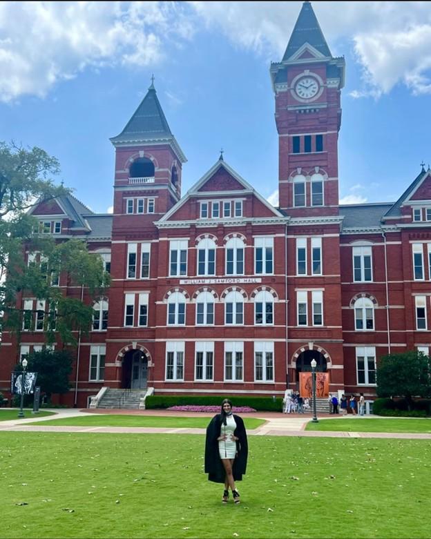 A woman standing in front of a brick building. 