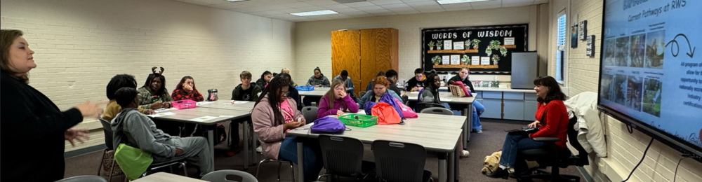 Students in a classroom sitting at desks with an adult leader