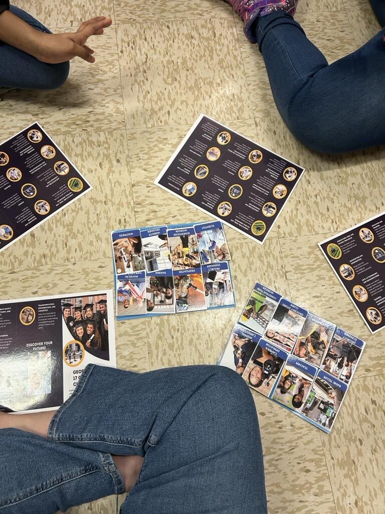 Students sitting on the floor reviewing materials on brochures.