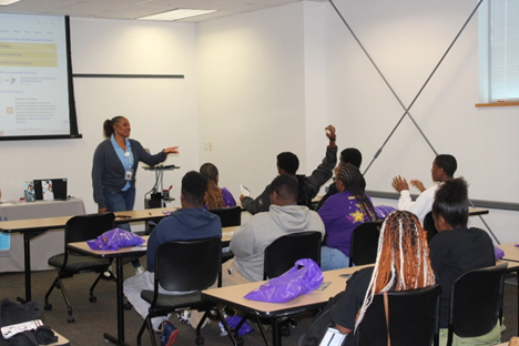 A GVRA representative wearing a GVRA blue shirt talking in front of a group students.
