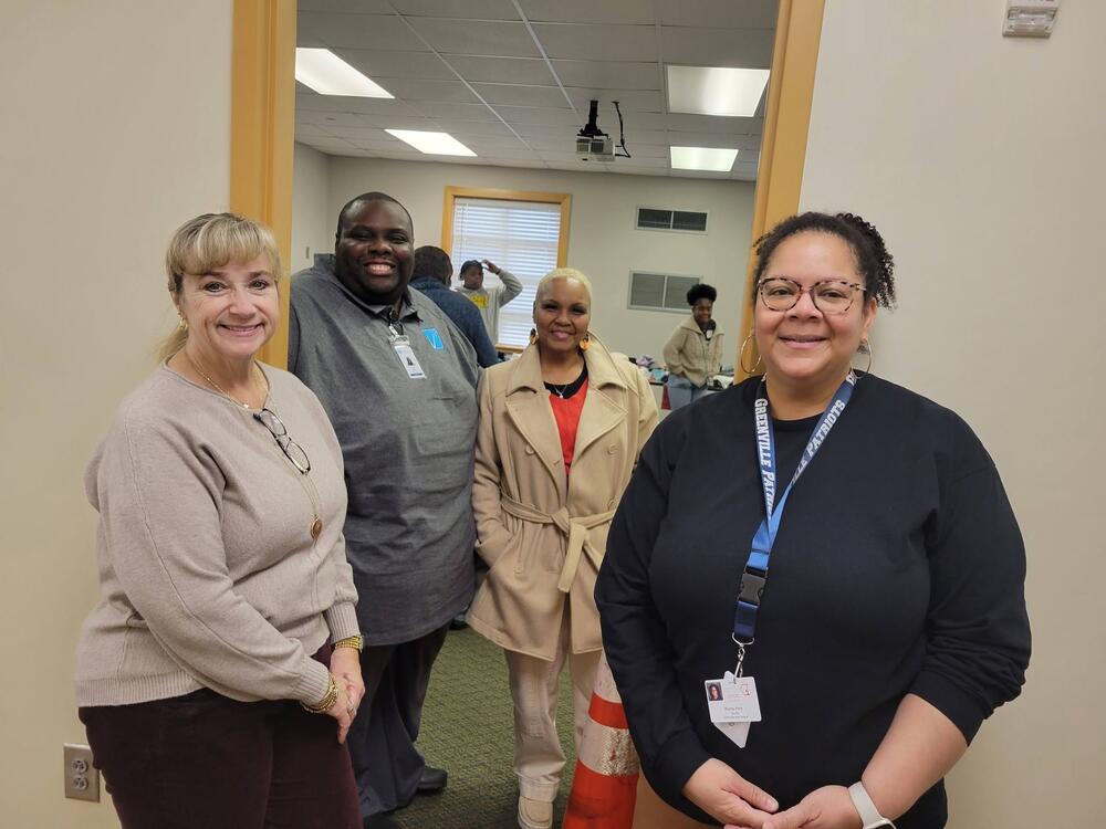 Four people standing in front of a door entrance smiling. 