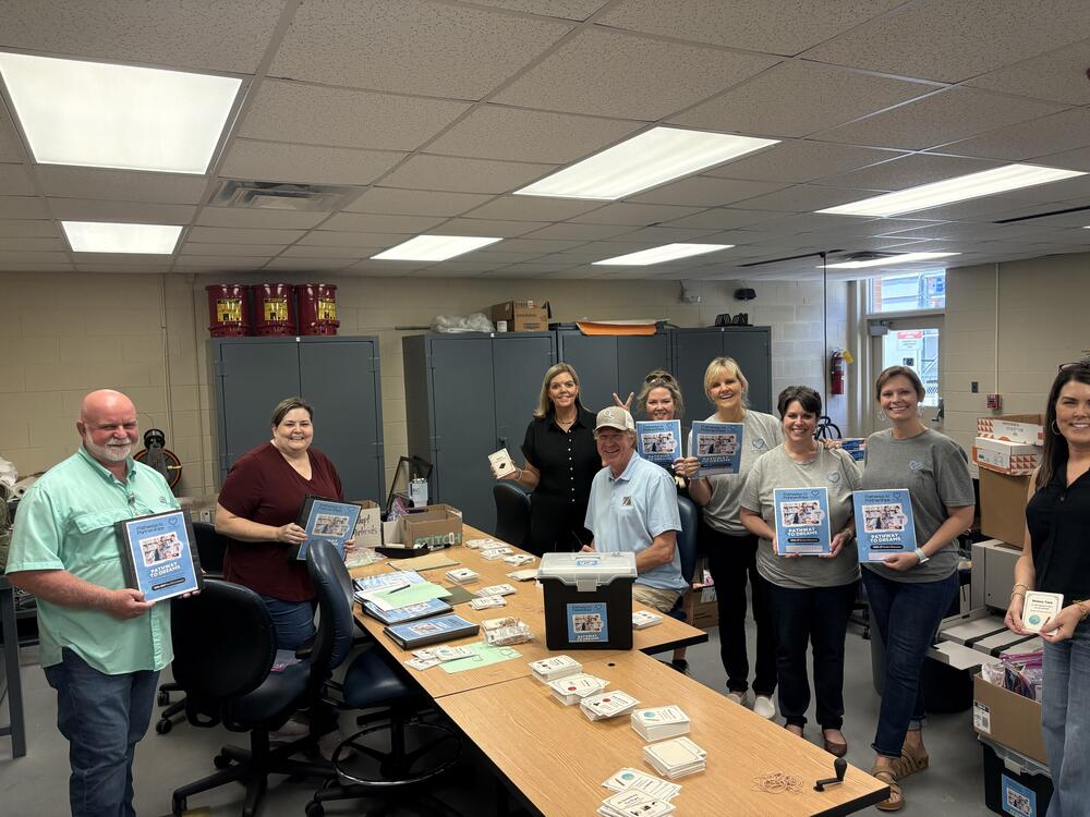 Group of people in a print shop with printed materials in their hands. 