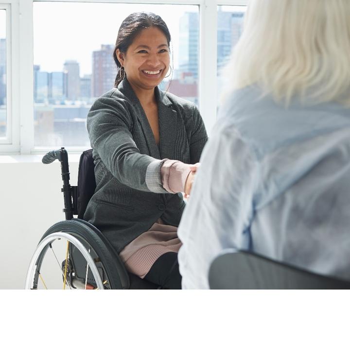 A person in a wheelchair shaking hands with another