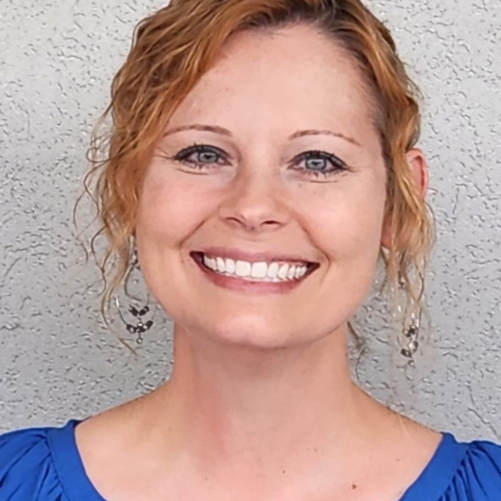 White woman with reddish-brown hair wearing a blue shirt