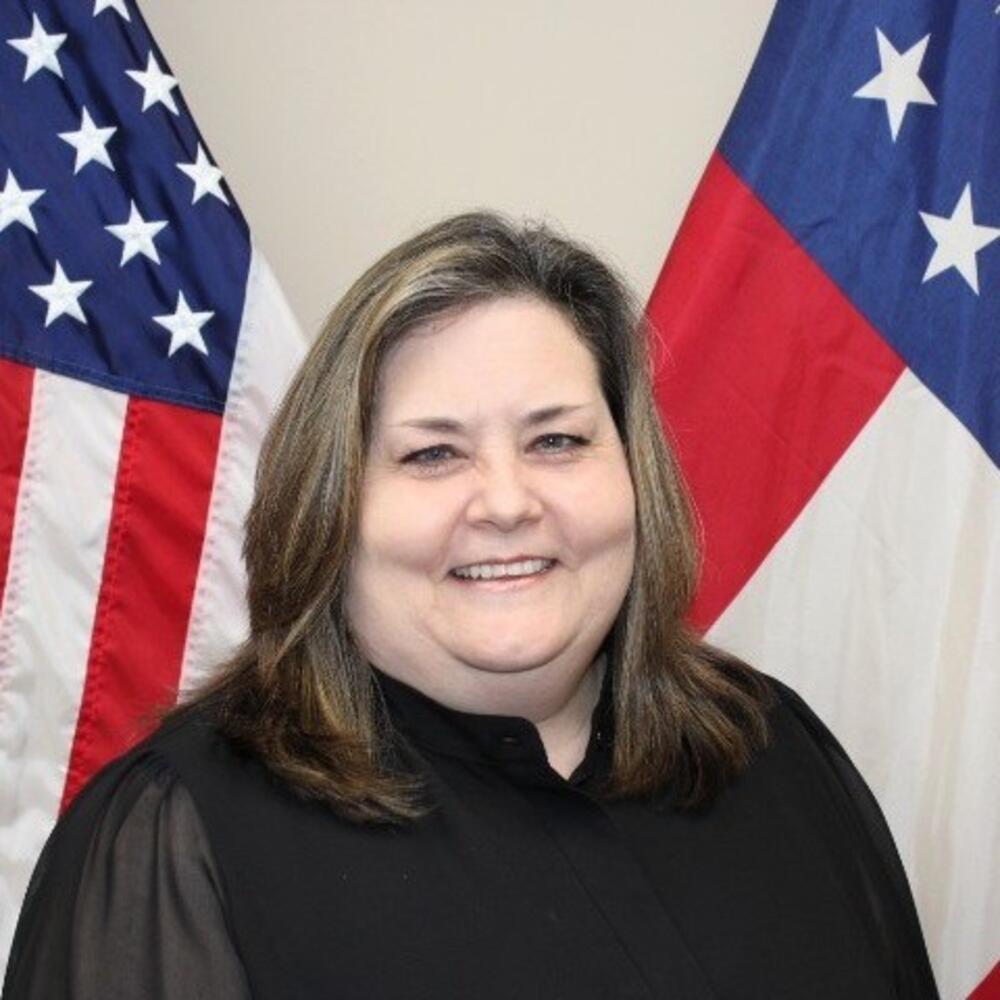 Woman with brown shoulder length hair wearing a black shirt