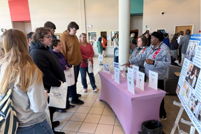 Group of people stand around table at transition fair