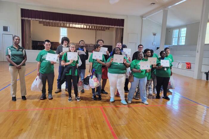 A group of students wearing green t-shirts and is holding a document in their hand. 